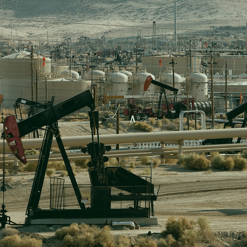 Oil pumpjacks in an open desert.