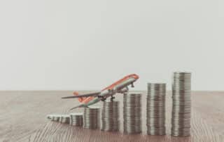 toy plane on stacks of coins on wooden table