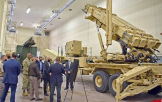 US Army Undersecretary and staff looking at a brown missile battery ina closed space