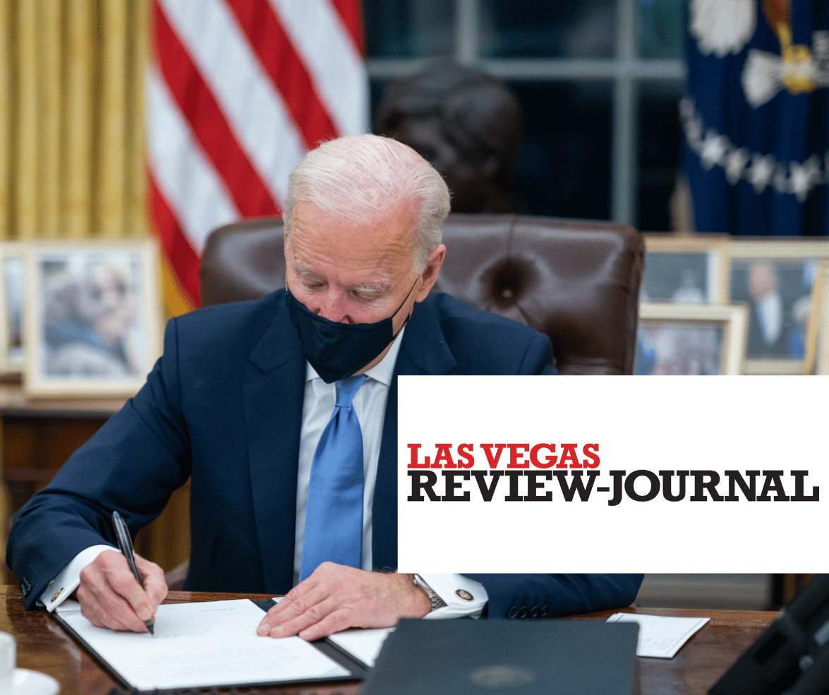 President Biden signing a document with afacemask on with the Las Vegas Review-Journal logo in the foreground