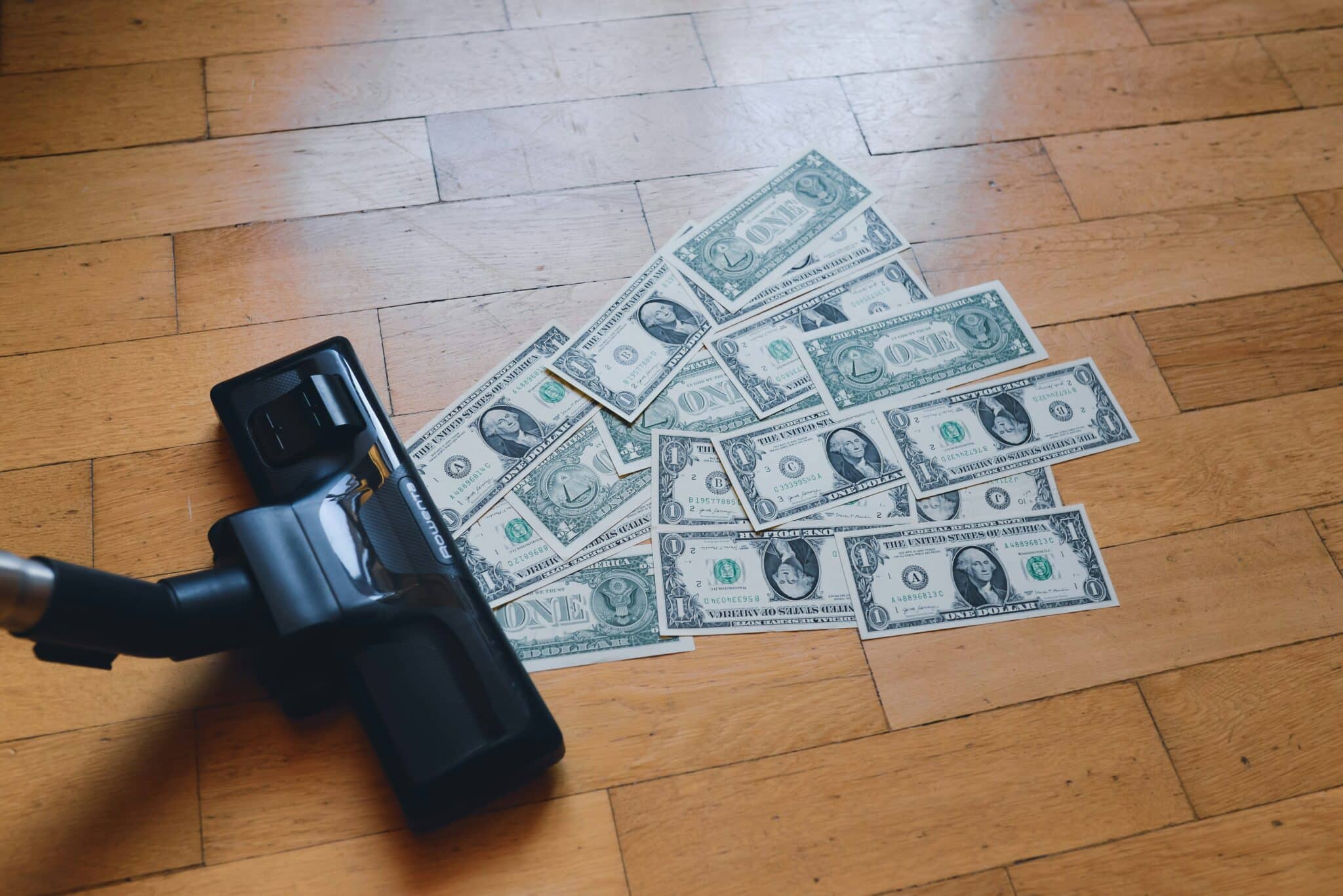 A vacuum cleaner sucking up 1 dollar bills