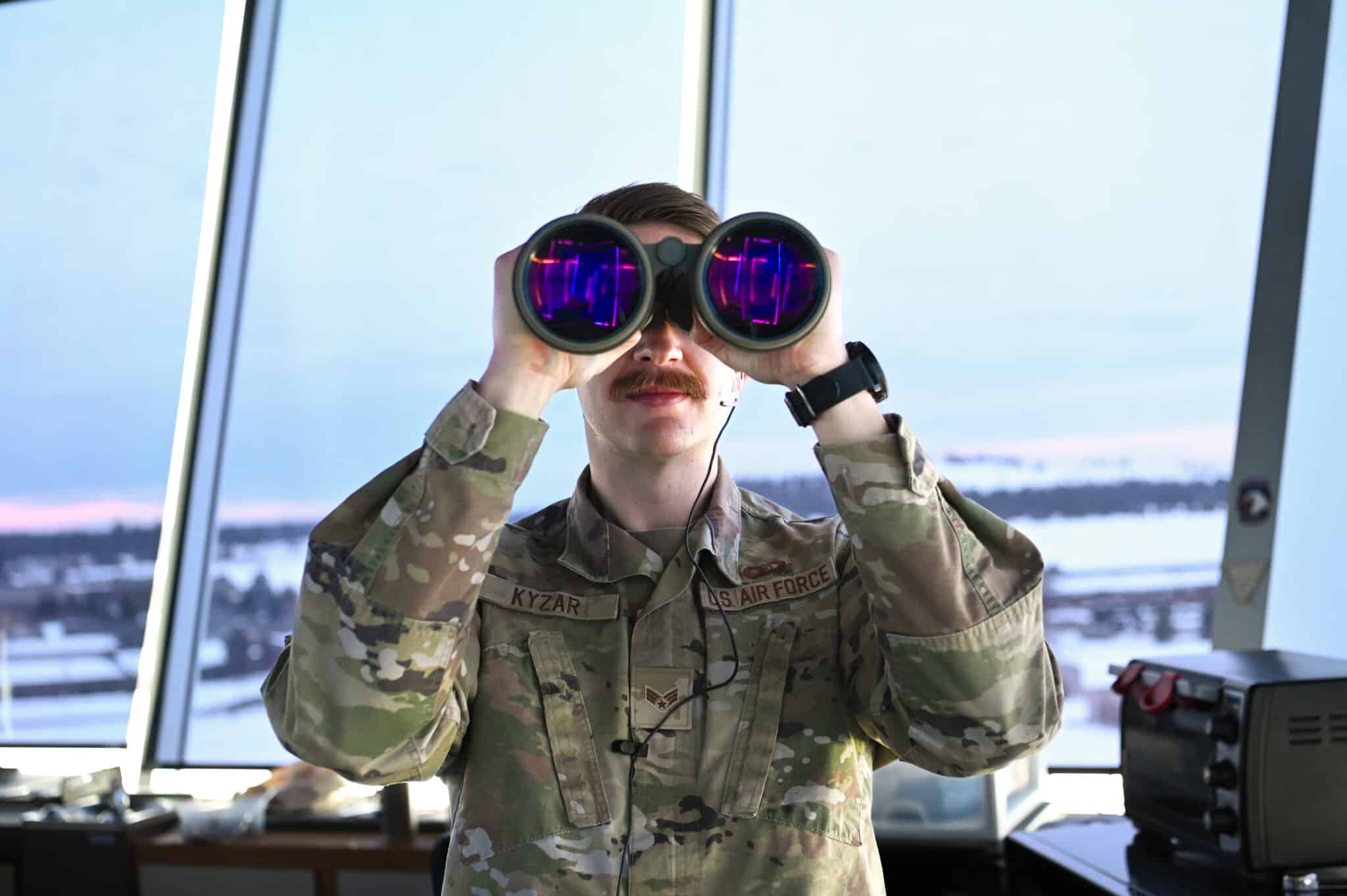 A soldier looks through large binoculars.