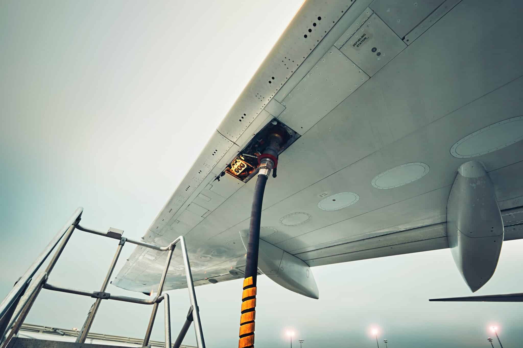 Aircraft fueling hose attached to the wing of a parked airplane