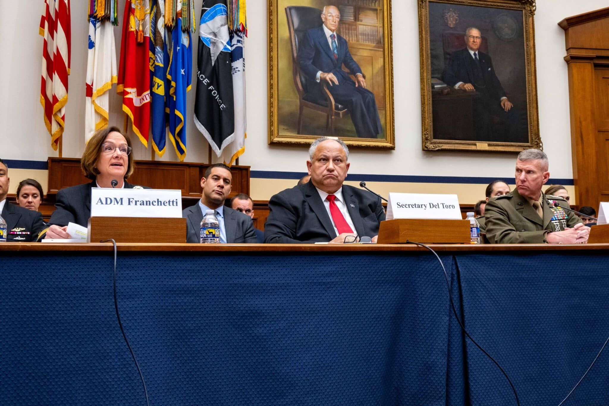 5 military officials sit at a table as they provide testimony